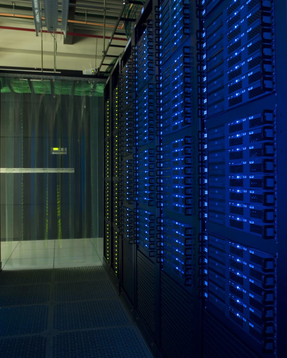 Pasillo de data center con una fila de racks de servidores con LED azules y cortina de contención al fondo