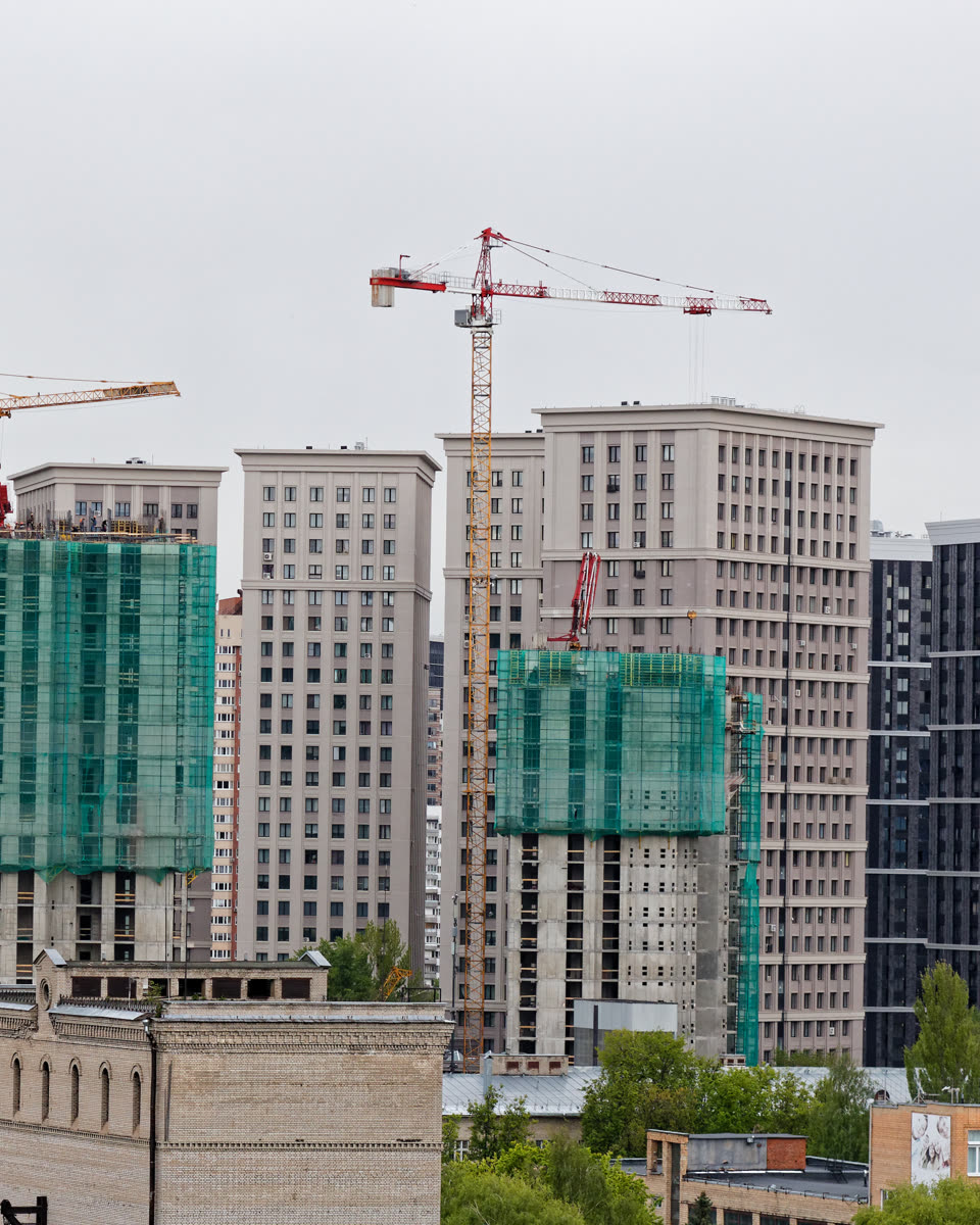 Edificios residenciales en construcción con grúas y malla de protección en la fachada