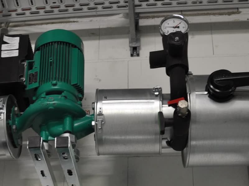 Green circulation pump on insulated piping, with a pressure gauge and valves